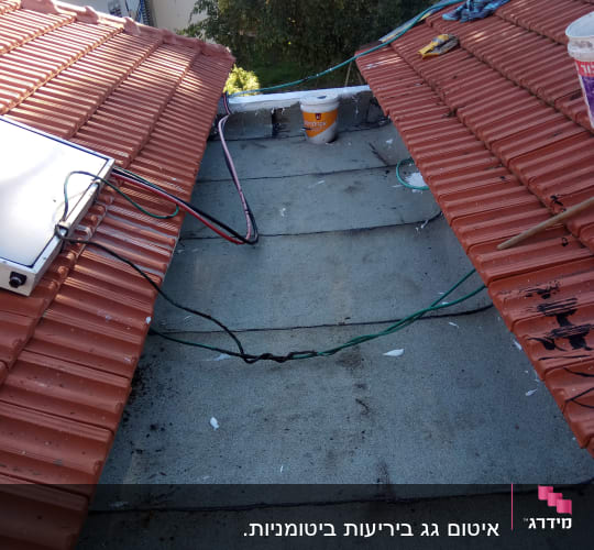 דלי צבע על גג עם רעפים אדומים